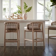 two wicker chairs sitting in front of a white table with potted plants on it