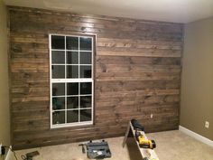 an empty room with wood paneling and tools on the floor next to a window