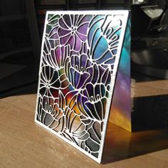 a card with stained glass flowers on it sitting on a table next to a keyboard