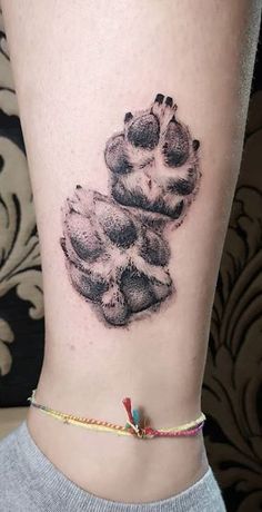 a black and white photo of a cat's paw tattoo on the right ankle