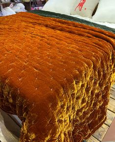 an orange bedspread on top of a wooden bed