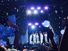 a group of people standing on top of a stage with their hands in the air