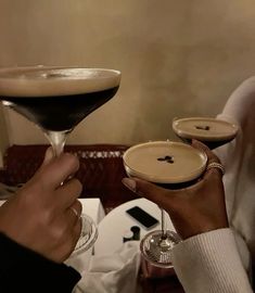 two people holding up martini glasses in front of each other