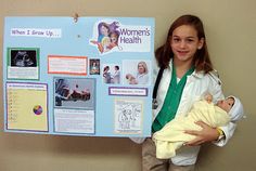 a young woman holding a baby next to a bulletin board with information about women's health