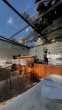 an outdoor kitchen with tables and chairs under a glass roof over looking the city below