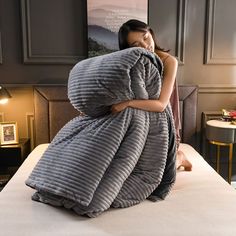 a woman wrapped in a blanket on top of a bed