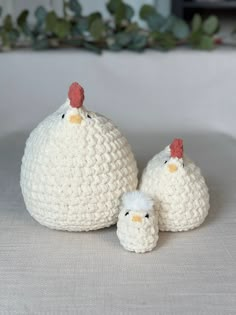 two small crocheted chickens sitting next to each other on a white tablecloth