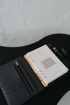 a black and gold binder on top of a desk next to a laptop computer