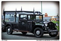 an old black car is parked on the side of the road