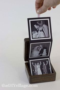 someone is placing pictures on top of each other in a small wooden box with the lid open