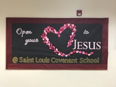 a banner hanging on the wall in a school room with hearts and words painted on it