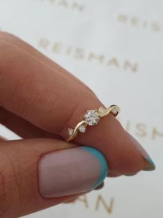 a woman's hand holding a gold ring with two diamonds on top of it