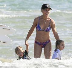 a woman and two children are in the water with their surfboards at the beach