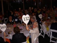 a group of people sitting around a table holding up heart shaped signs with numbers on them