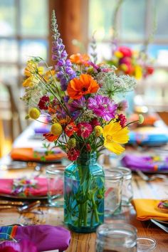 a vase filled with colorful flowers sitting on top of a table next to plates and napkins