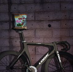 a bike parked next to a brick wall with a bag on the back tire and an advertisement for food