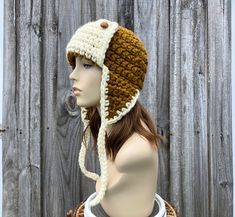 a mannequin head wearing a crocheted hat on top of a wooden fence