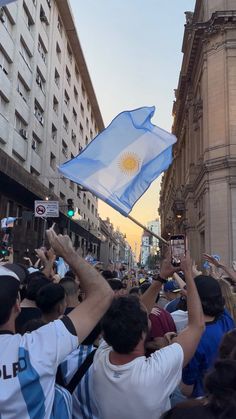 a group of people holding up flags and cell phones in the air on a city street