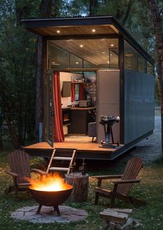 a small house with a fire pit in the middle of it and chairs around it