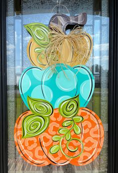 a glass door decorated with colorful pumpkins and leaves in front of a building window