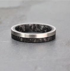 a close up of a wedding ring on a gray surface with black and white marble