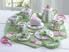 a table topped with tea cups and plates covered in crochet