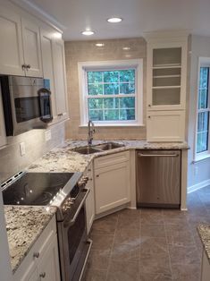 a kitchen with marble counter tops and white cabinets