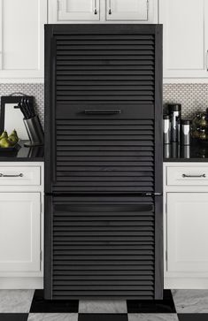 a black refrigerator freezer sitting inside of a kitchen next to white cabinets and counter tops