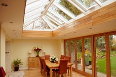 a dining room with wooden floors and large windows on the ceiling is filled with flowers