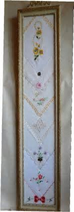 an embroidered wall hanging in a frame with flowers and hearts on the bottom half of it