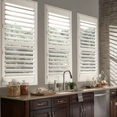 a kitchen with wooden cabinets and white blinds on the windows over the sink is shown