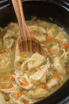 a wooden spoon in a slow cooker filled with tortellini soup and vegetables