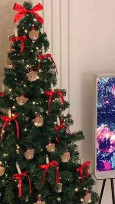 a small christmas tree with teddy bears on it next to a television set and other decorations