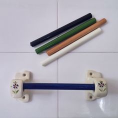 three pencils and two erasers on a white tile floor, one with blue handles