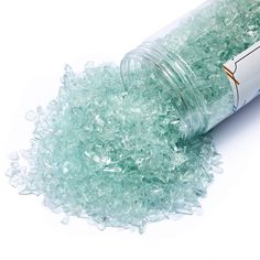 a jar filled with sea glass sitting on top of a white table next to a pile of ice