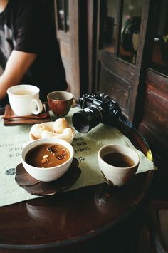 two bowls of soup are sitting on a table next to a pair of camera's