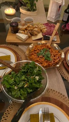 the table is set with many plates and bowls of food, including bread, salad