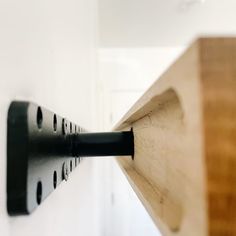 a close up of a piece of wood on a wall with a black object hanging from it's side