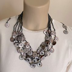 Charcoal Gray Multi-Strand Necklace Made With Seed Beads And Pearlescent “Buttons” With Sequins On Each Side Of The Button Hole. There Are Five Strands With Silver End Caps And Short Silver Chain Which Allows You To Adjust This Necklace From Approx. 18”-20". A Pair Of Matching 3” Dangle Earrings With A Fishhook Post Complete The Set. Nwot ... I Never Wore This Set. I Have Too Much Jewelry And Am Beginning To Downsize My Collection. Unless Otherwise Noted As Being In Its Original Box, All Jewelry Silver Beaded Shell Necklace With Round Beads, Multi Strand Beaded Necklace, Button Necklace, Button Hole, Necklace And Earrings Set, Button Jewelry, Button Art, Jewelry Card, Multi Strand Necklace