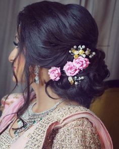 a woman with flowers in her hair is wearing a pink and gold sari dress