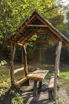 a wooden picnic table and bench in the woods