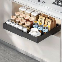 an open drawer in a kitchen filled with spices and other food items next to a sink