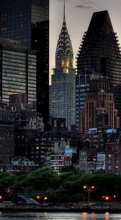 there are many tall buildings in the city at night time as seen from across the river