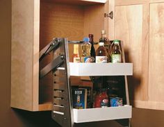 a pull out spice rack with spices and condiments in the bottom drawer is open