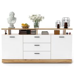 a white and wood sideboard with books, vases and flowers on top of it