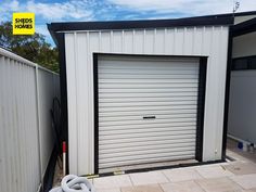 a white garage with a door open next to a fenced in area and a hose on the ground