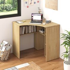 a computer desk with a laptop on top of it next to a potted plant