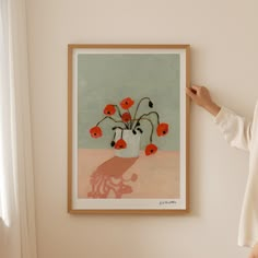 a woman standing in front of a painting on the wall with her hand up to it