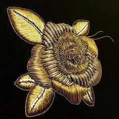 an embroidered gold flower is shown on a black background