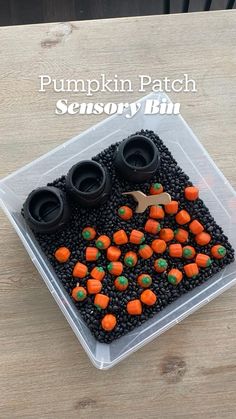 a plastic container filled with black and orange candies on top of a wooden table